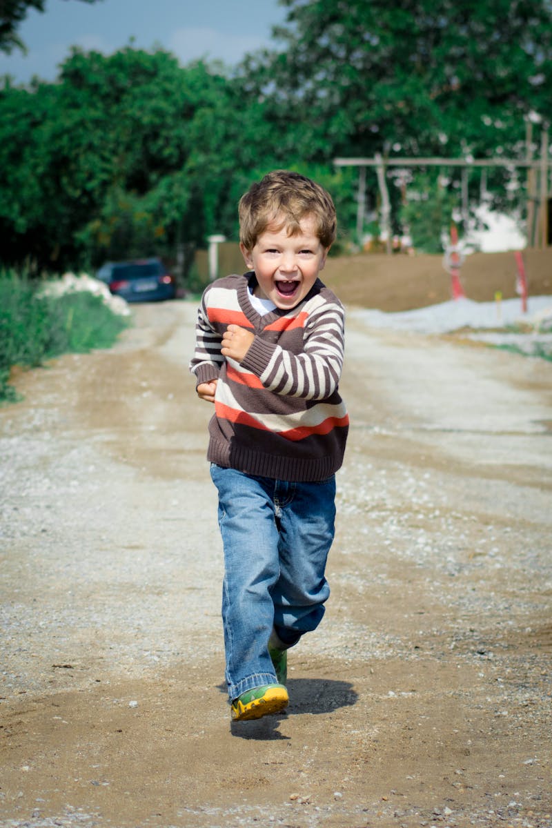 A young boy joyfully runs down a path, showcasing playful energy in a Czech outdoor setting.